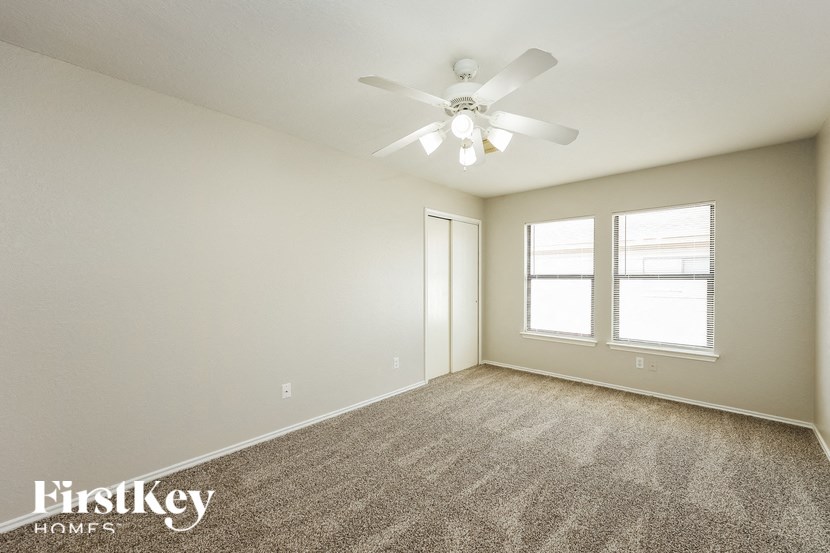 a spacious living room with carpet and a ceiling fan