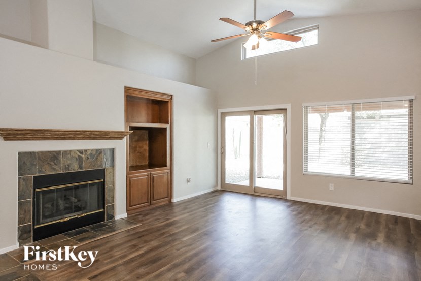 an empty living room with a fireplace and a ceiling fan