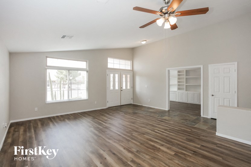 an empty living room with a ceiling fan