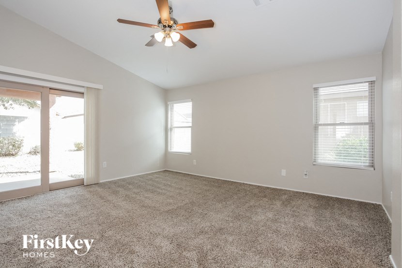 an empty living room with a ceiling fan and a window