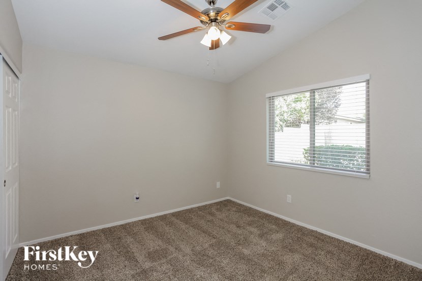 an empty bedroom with a ceiling fan and a window