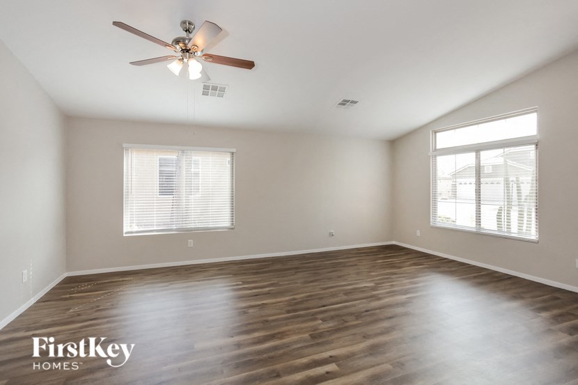 an empty living room with wood floors and a ceiling fan