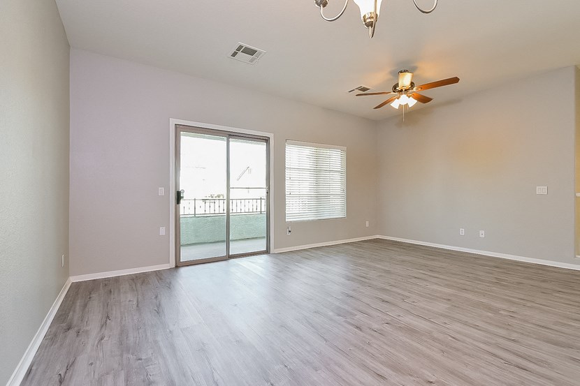 an empty living room with a ceiling fan and a sliding glass door