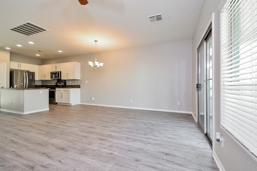 an empty living room and kitchen with white walls and wood flooring