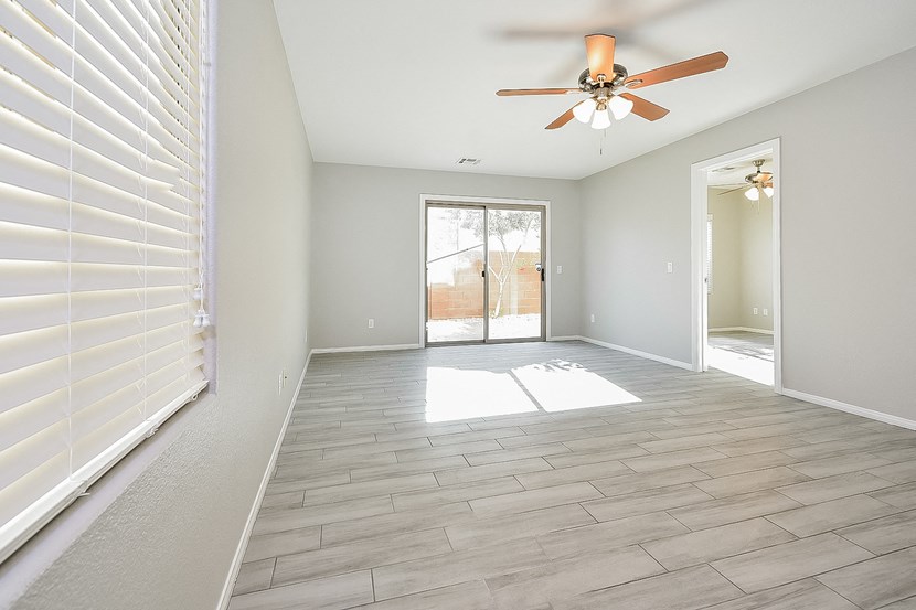 an empty living room with a ceiling fan and a door to a patio