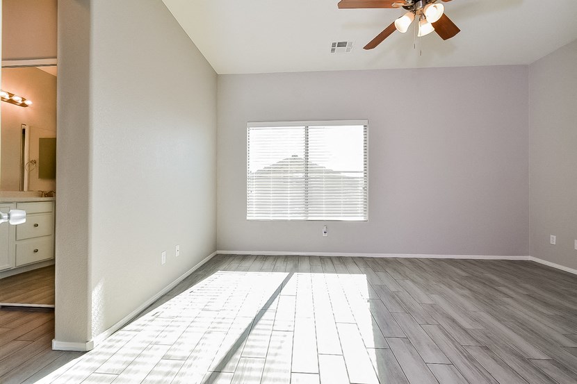 an empty living room with a window and a ceiling fan
