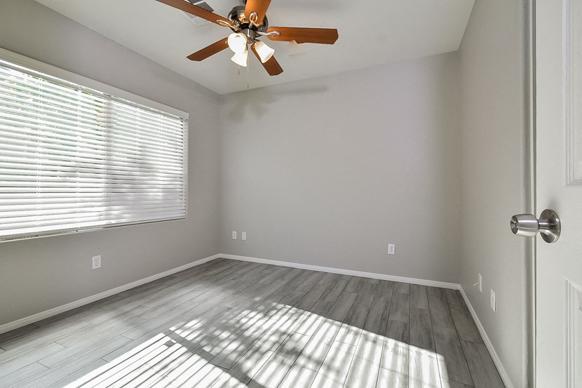 an empty bedroom with a ceiling fan and a window