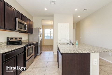 A kitchen with a granite countertop and a stove top oven.