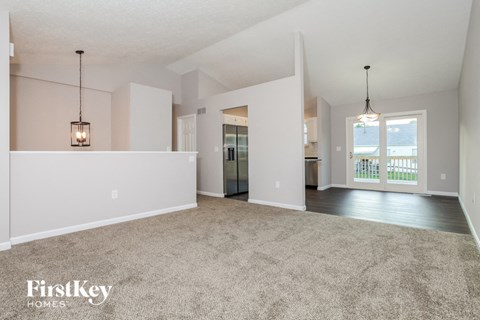 A spacious living room with a carpeted floor and a large window.