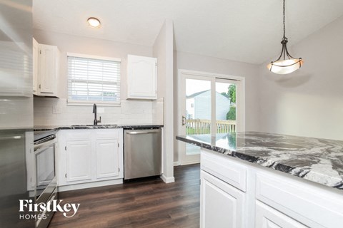 A kitchen with white cabinets and a marble countertop.