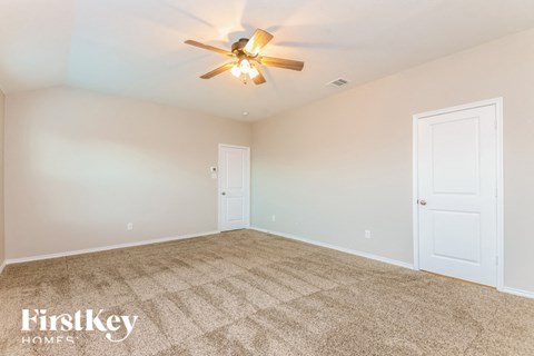 the spacious living room with carpeted flooring and a ceiling fan