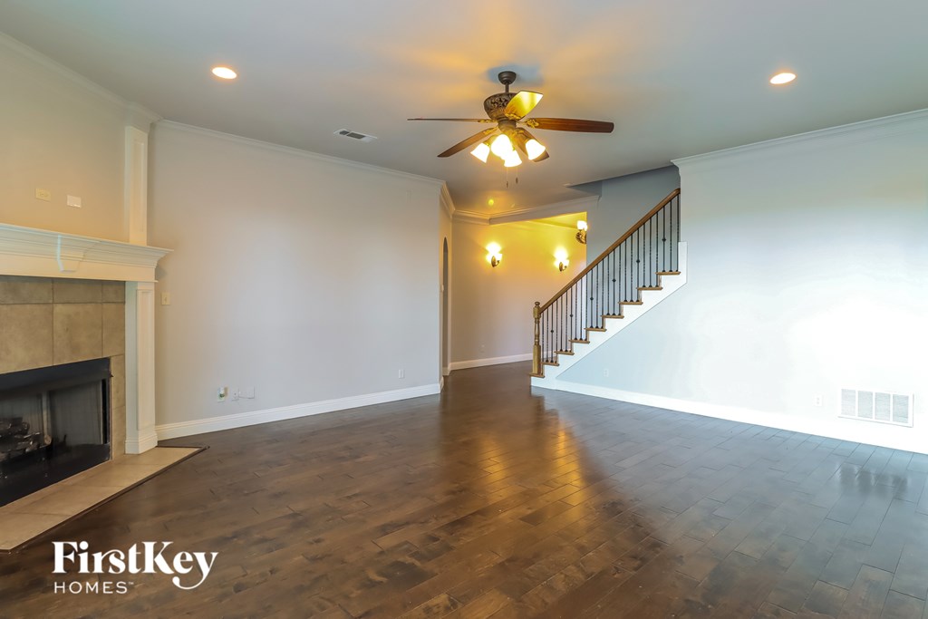 A spacious living room with a fireplace and a staircase.