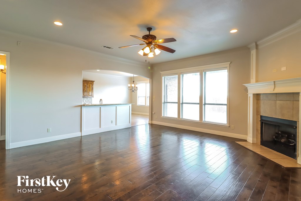 A spacious living room with a fireplace and a ceiling fan.