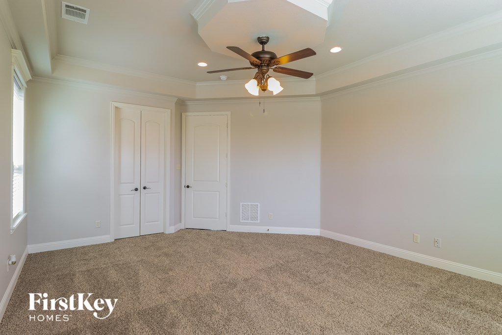 A room with a ceiling fan and carpeted floor.
