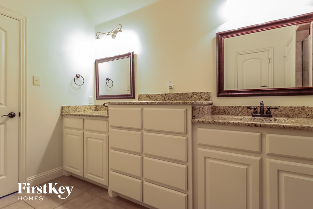 A bathroom with a sink, mirror, and cabinets.