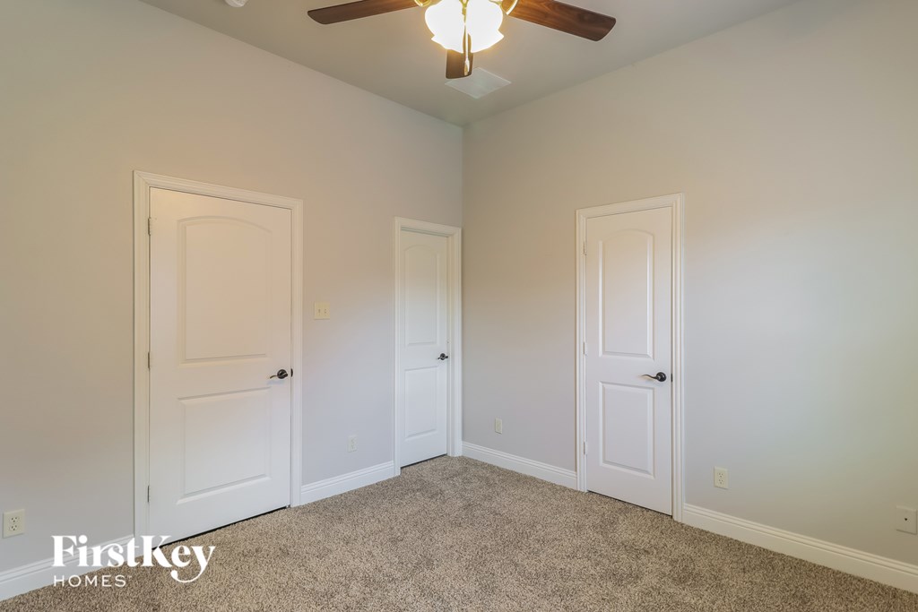 A room with a carpet floor and a ceiling fan.