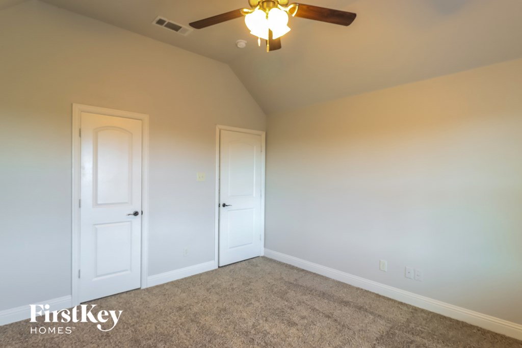 A room with a ceiling fan and two doors.