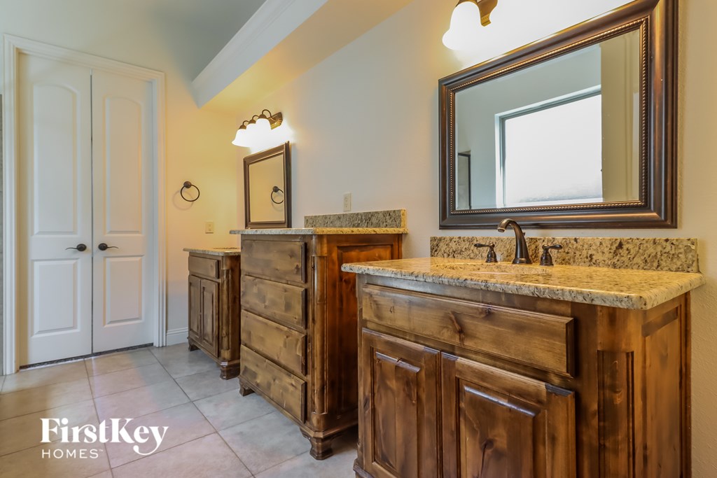 A bathroom with a wooden vanity and a mirror above it.