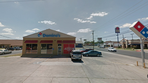 A Domino's Pizza store with cars parked in front.