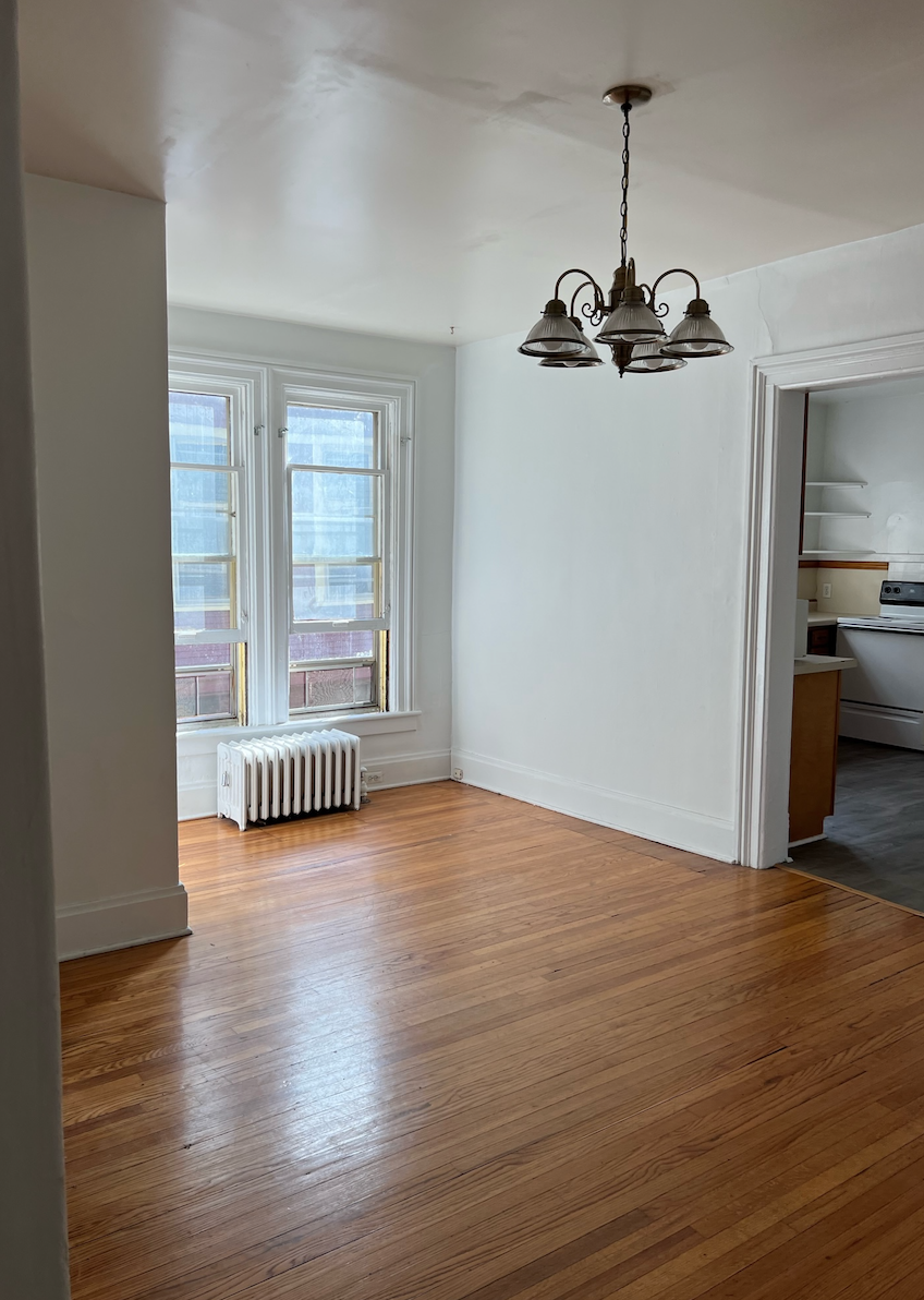 an empty living room with a hard wood floor and a chandelier