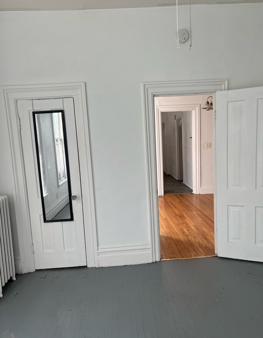 a room with three doors and a mirror on the wall