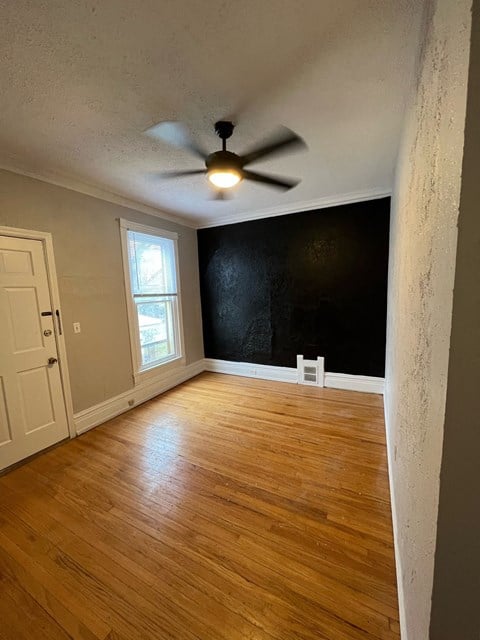 an empty living room with a black wall and a ceiling fan