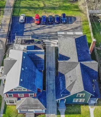 an aerial view of a building with blue roofs and a parking lot with cars