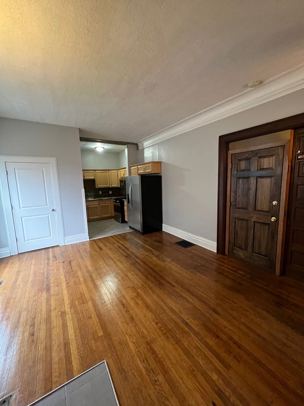 an empty living room with wooden floors and a kitchen