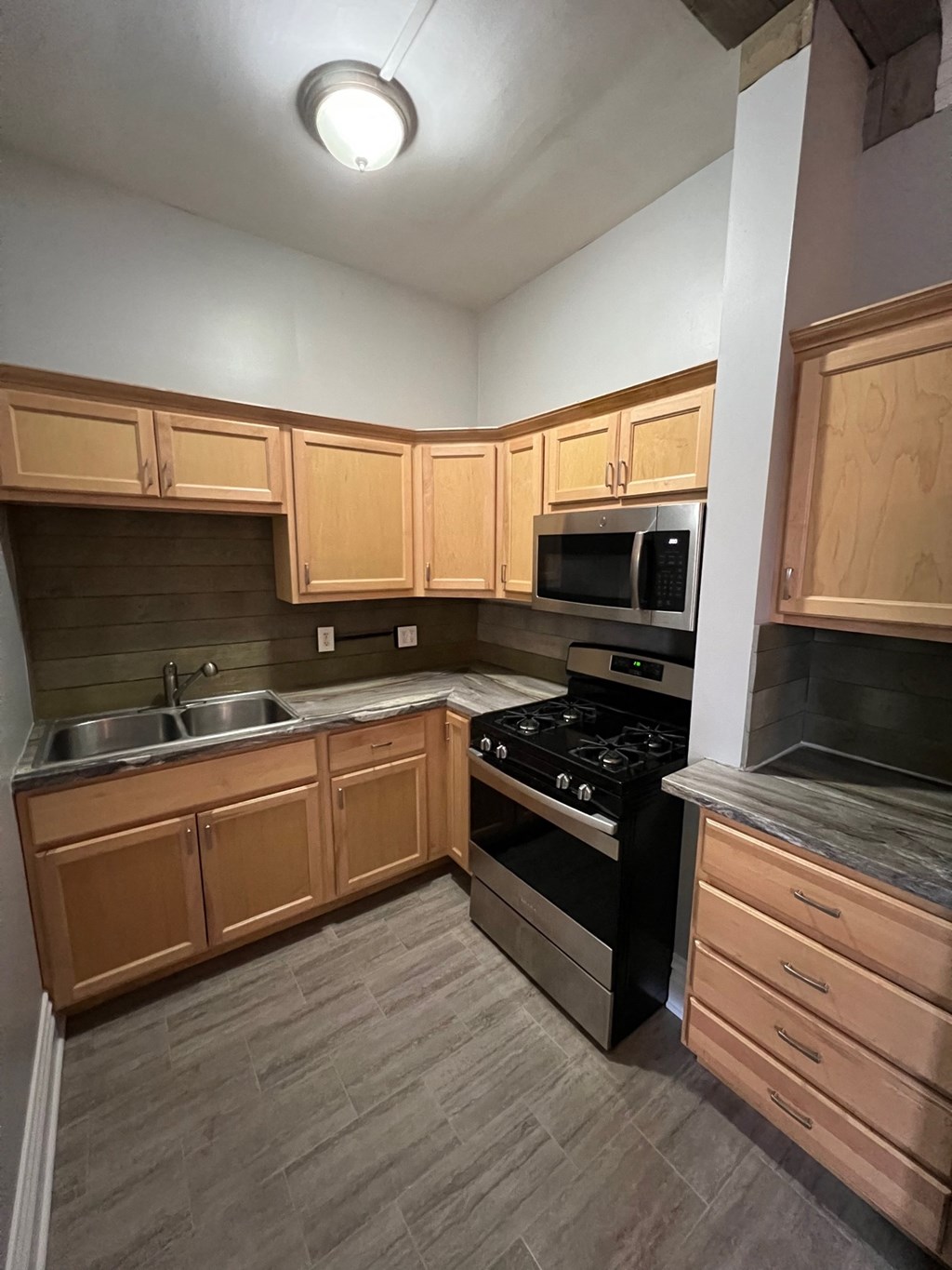 an empty kitchen with wooden cabinets and black appliances