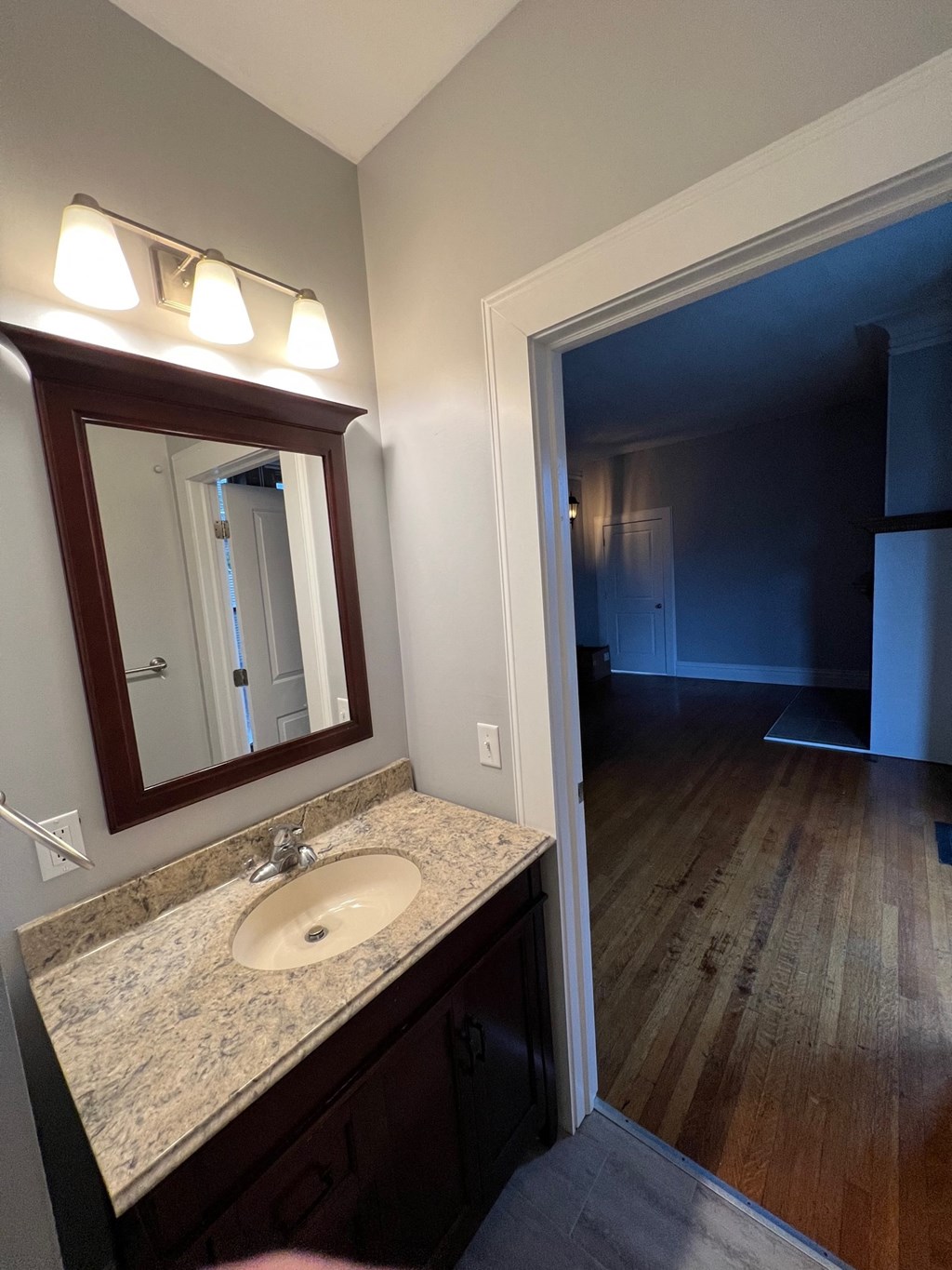 a bathroom with a sink and a mirror and a hallway