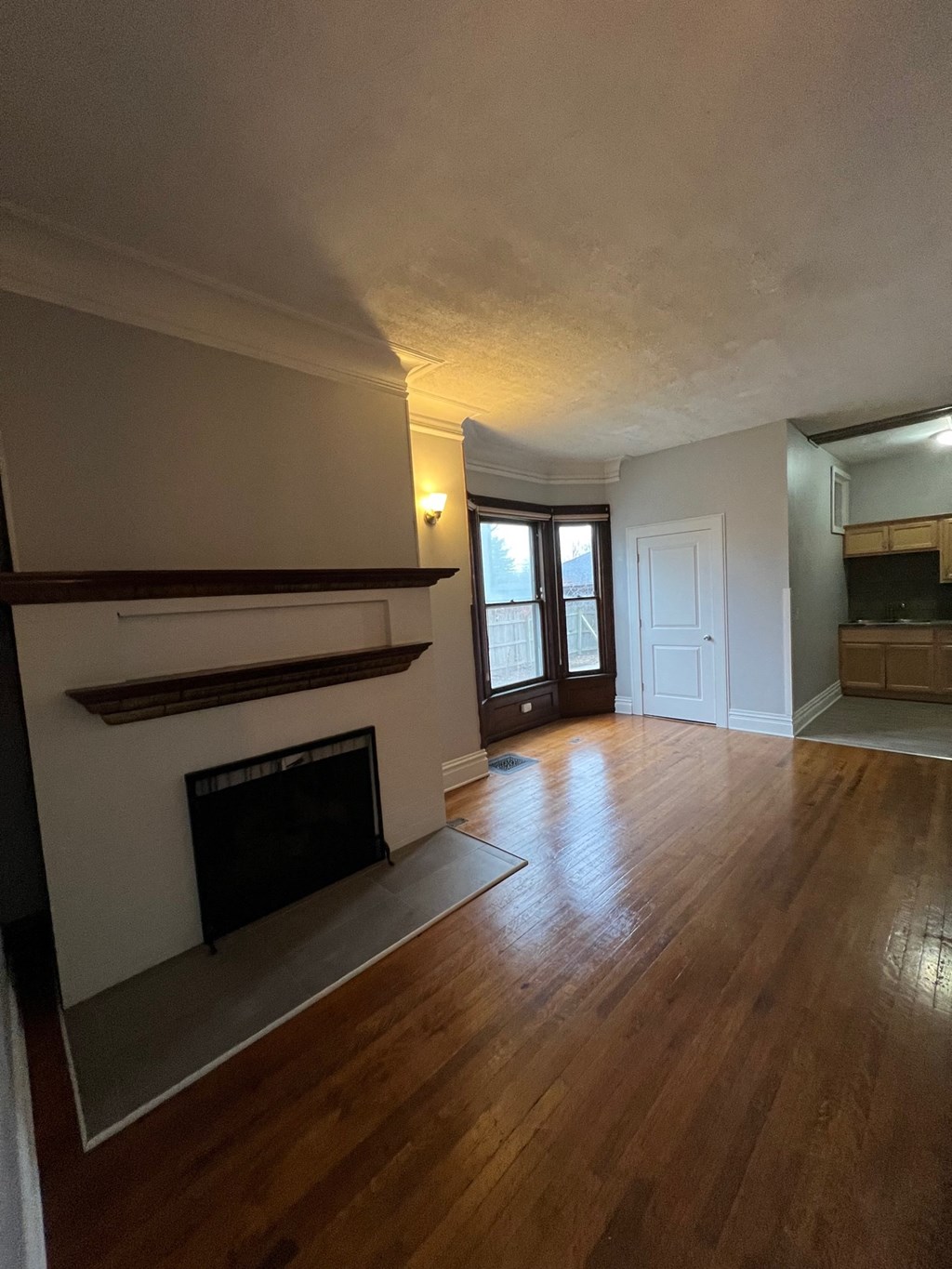 an empty living room with a fireplace and wooden floors