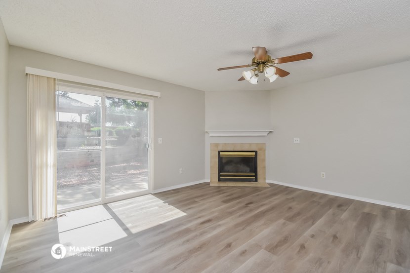 an empty living room with a fireplace and a ceiling fan