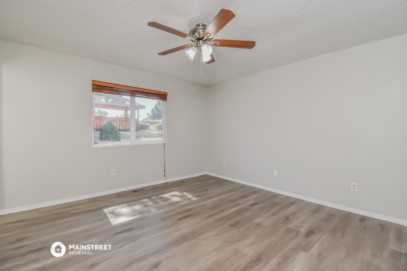 the spacious living room with ceiling fan and wood flooring