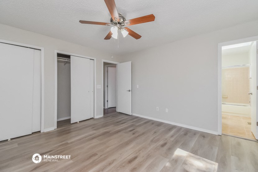 an empty living room with a ceiling fan and white walls