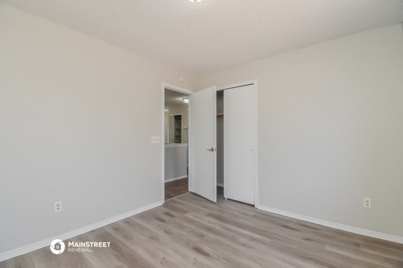 a spacious living room with white walls and wood flooring