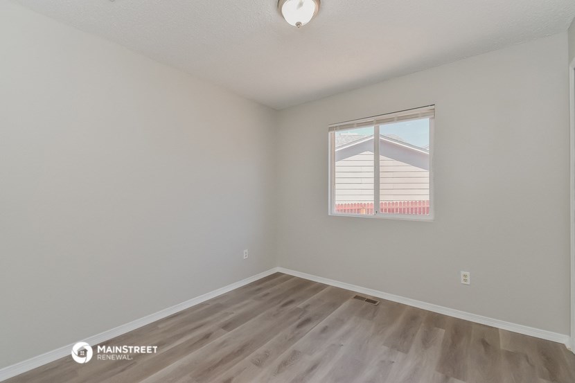 the living room of an apartment with wood flooring and a window