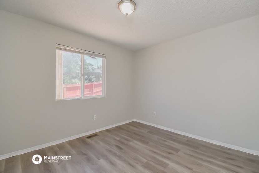 the living room of an empty house with wooden floors and a window