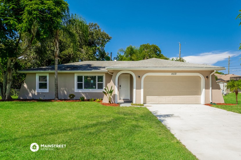 a beige house with a lawn and a driveway