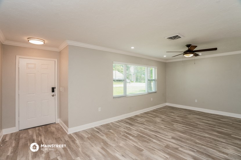 the living room with a white door and a ceiling fan