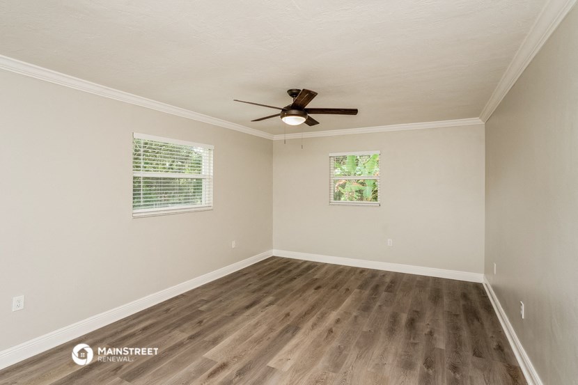 the spacious living room with hardwood floors and a ceiling fan