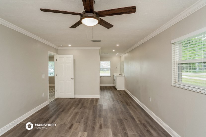 the spacious living room with a ceiling fan