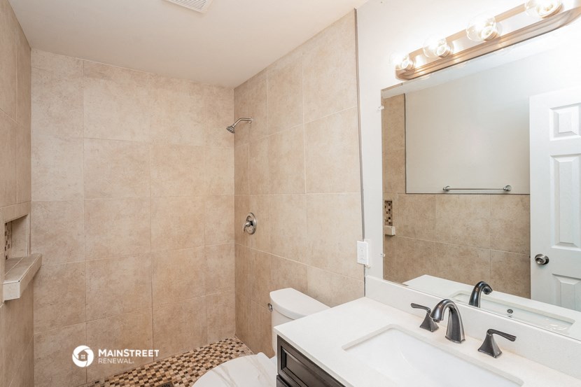 a bathroom with a sink toilet and shower and a mirror