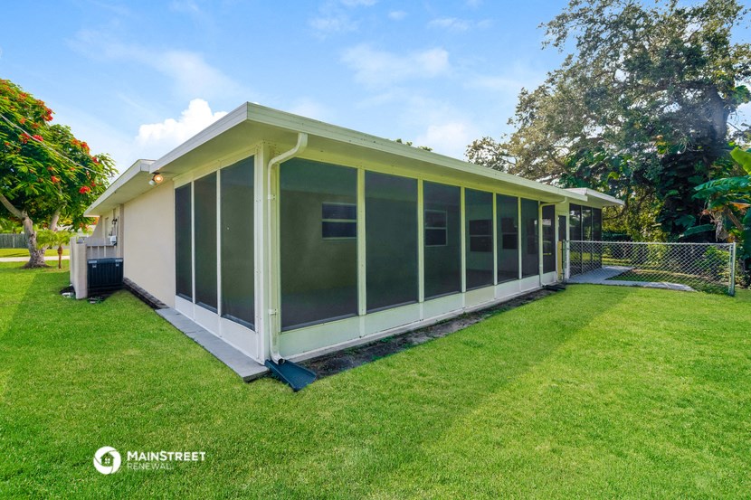 a home with a screened in porch and a lawn