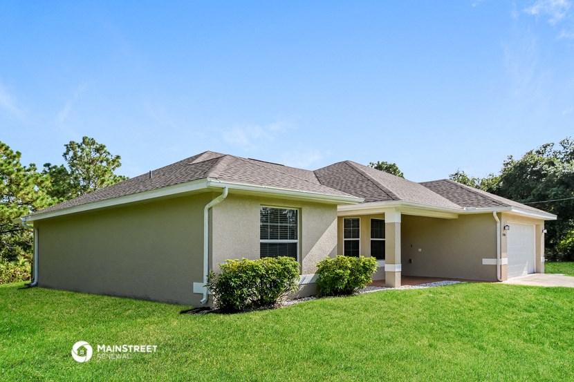 a beige house with a lawn and some bushes