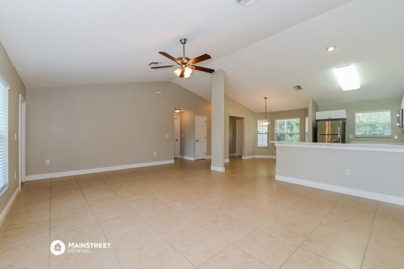 an empty living room with a ceiling fan