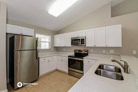 the kitchen has stainless steel appliances and white cabinets