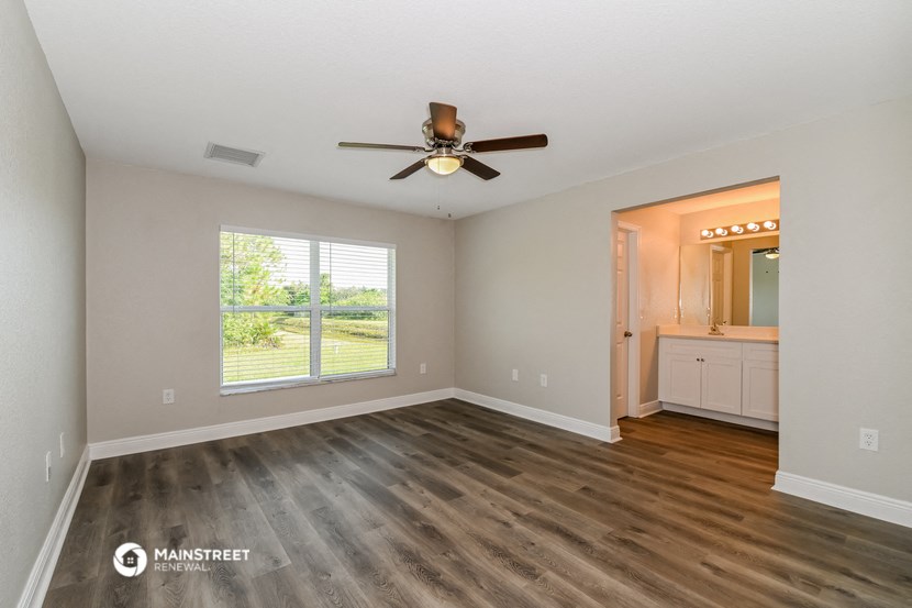 an empty living room with a ceiling fan and a window