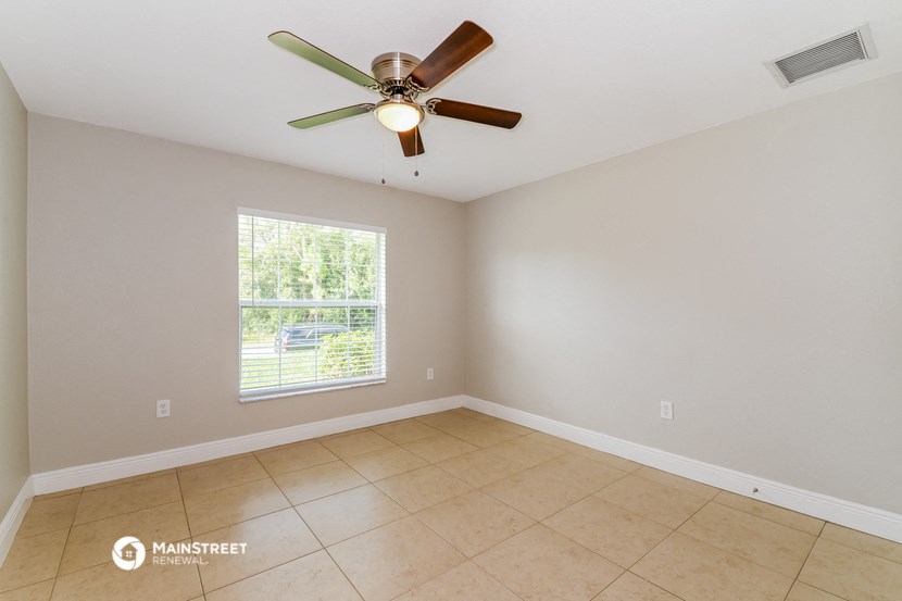 an empty living room with a ceiling fan and a window
