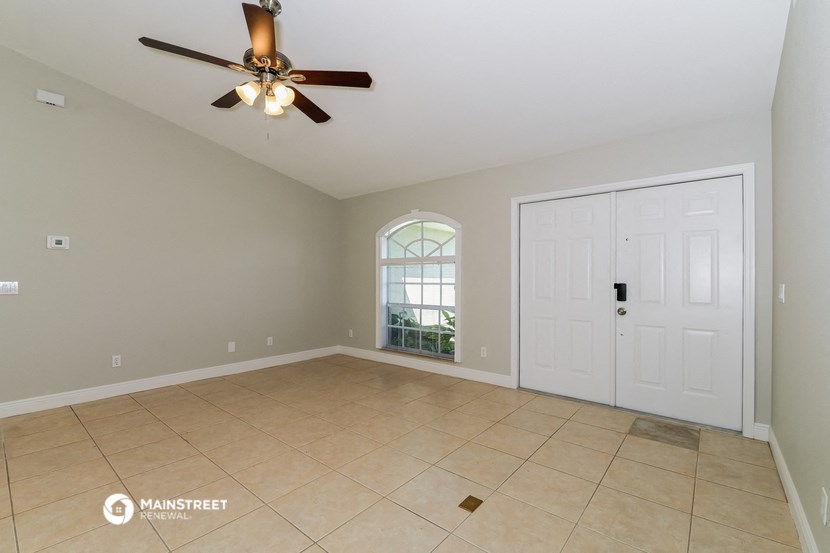 an empty living room with a ceiling fan