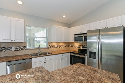 the kitchen has granite counter tops and stainless steel appliances